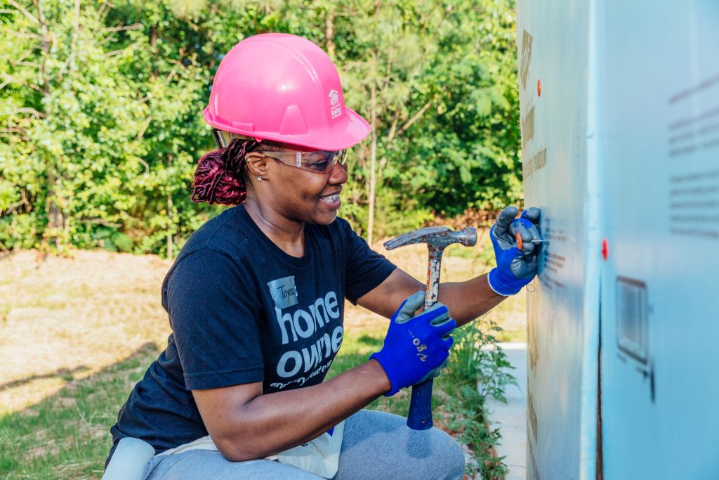 Future homeowner Toyea builds with Southern Crescent Habitat for Humanity during Women Build week. © She is hammering a nail into the exterior of the house.